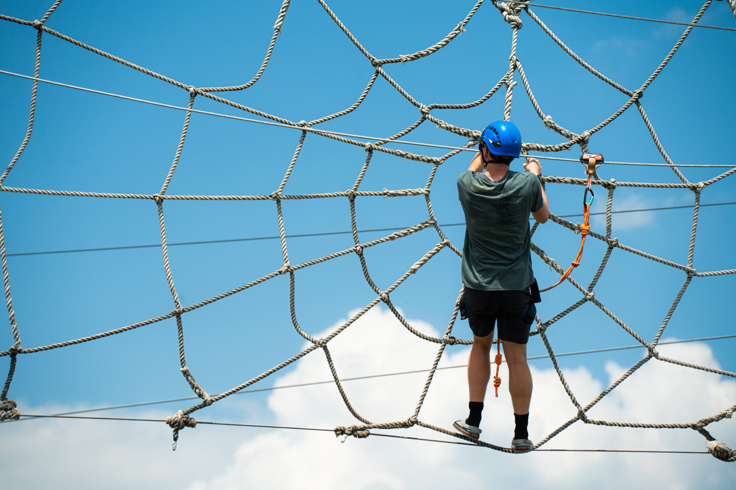 Child on Spider Monkey Aerial Adventure Course with Blue Skies in the background.