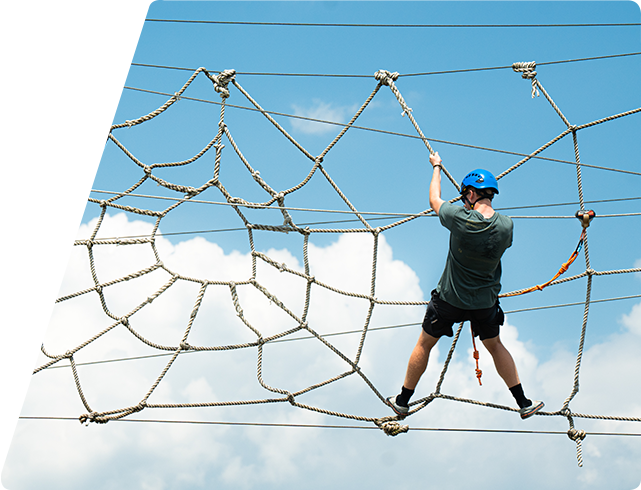 Child on Spider Monkey Aerial Adventure Course with Blue Skies in the background.