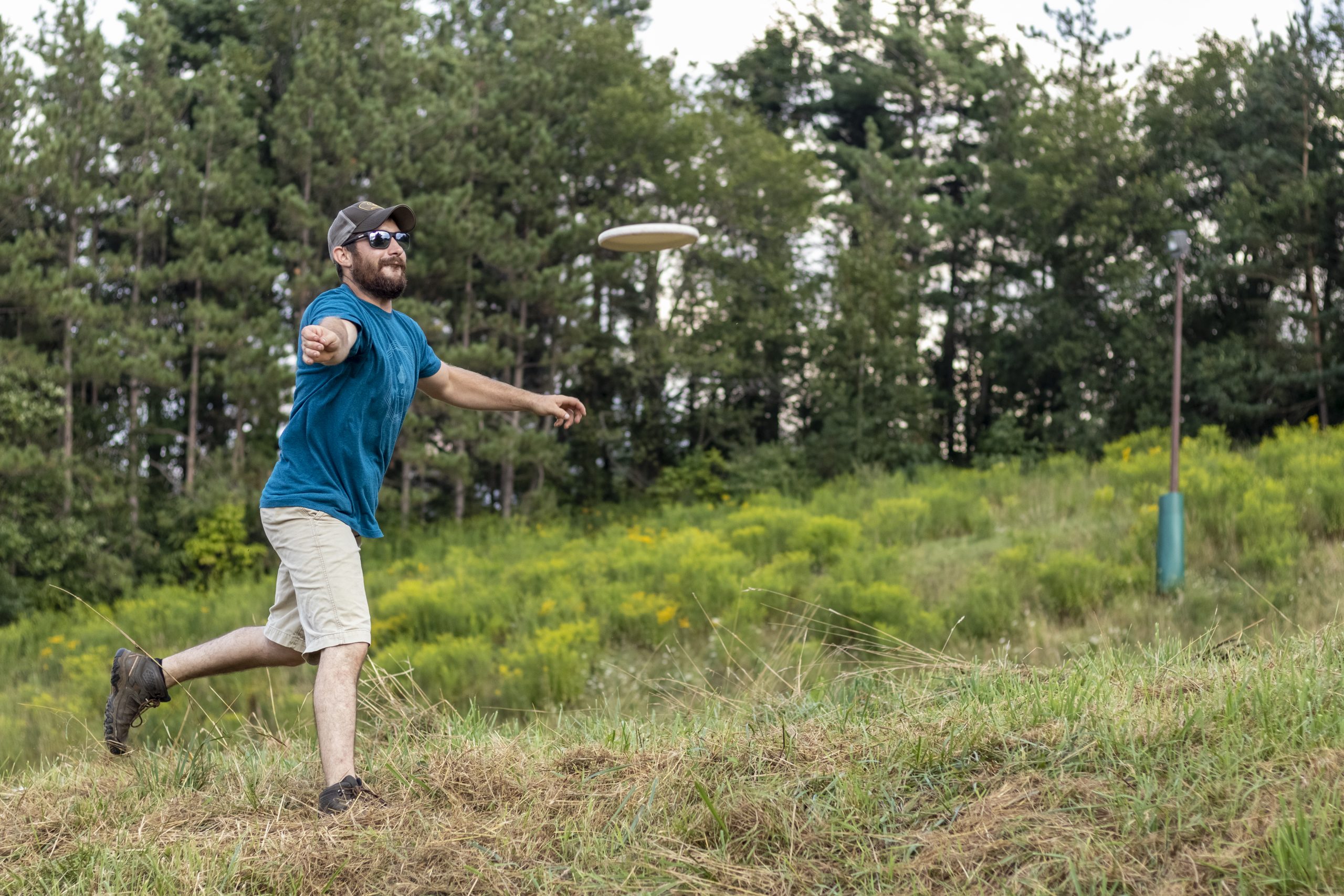 Man participating in disc golf and smiling.